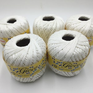 May include: Five white balls of yarn with yellow and blue labels that say "L'Gioco" on them.