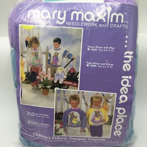 May include: A Mary Maxim Inc. needlework and crafts pattern package featuring a design for a children's pullover sweater with a mouse and baby motif. The pattern is titled "Children's Pullover Designer Originals" and includes instructions for sizes 4-6-8-10. The package includes yarn in shades of blue, purple, and white.