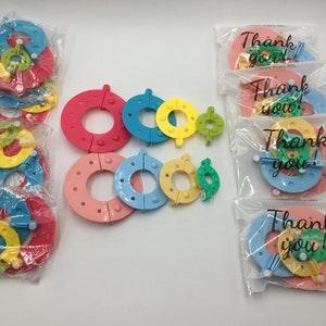 May include: A set of colourful plastic loom rings in various sizes, packaged in clear plastic bags. The bags have the text "Thank you!" printed on them.
