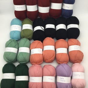 May include: Twenty-four balls of yarn in a variety of colours, including bright red, duck egg blue, indigo, meadow green, black, coral peach, basil green, pine green, rose, soft orchid, and quartz. Each ball has a white label with the colour name printed on it.
