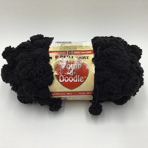 May include: A black ball of Red Heart Pom-Pom Doodle yarn. The label reads "Super Bulky 6 Super Abultado" and "Pom-Pom Doodle".