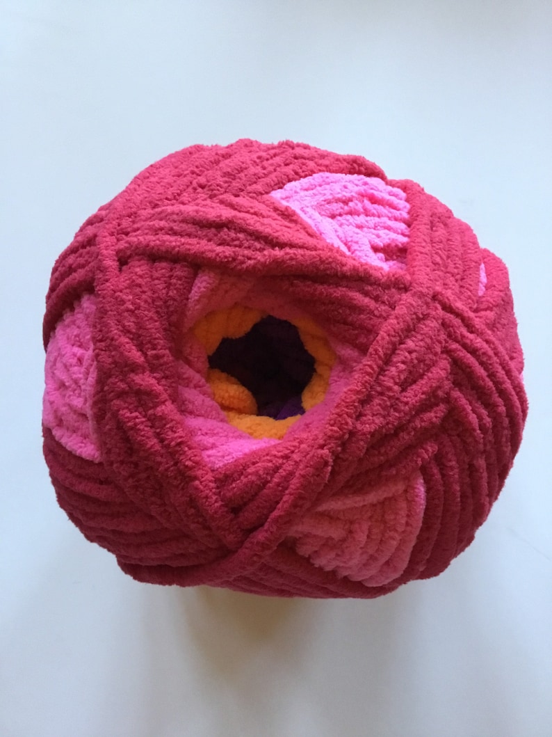May include: A ball of yarn with a pink, orange, and purple color gradient. The yarn is soft and fluffy, and it is perfect for knitting or crocheting.