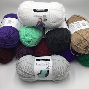 May include: Assortment of yarn skeins in various colours, including white, green, purple, grey, brown, and red. The yarn is labelled "Impeccable" and includes a pattern for a throw blanket.
