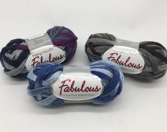 May include: Three skeins of Mary Maxim Fabulous ribbon yarn in different color combinations. The yarn is a mix of blue, gray, and purple.