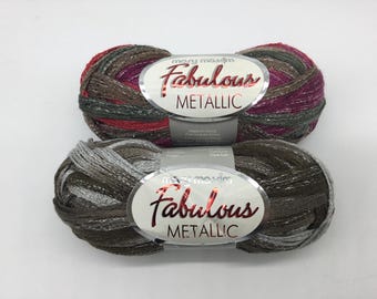 May include: Two skeins of yarn in a metallic silver and brown colorway and a metallic red, silver, and brown colorway. The yarn is labeled "Mary Maxim Fabulous Metallic".