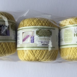 May include: Three skeins of yellow Bernat Handicrafter crochet thread, each weighing 3 ounces (85 grams). The label reads "100% Acrylic/Acrylique/Acrilico" and "Bernat Handicrafter Crochet Thread/Fil de crochet/Hilo para tejer a ganchillo".