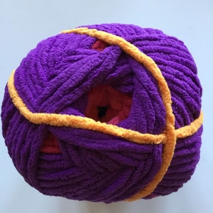 May include: A ball of purple yarn with a yellow stripe wrapped around it. The yarn is soft and fluffy, and it is perfect for knitting or crocheting.