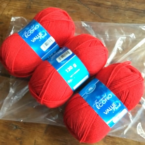 May include: Three balls of red yarn with blue labels that say "Formel Econo Value Yarn" and "120 g".