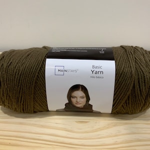 May include: A skein of Mainstays Basic Yarn in a dark olive green colour. The label reads "Basic Yarn" and "Hilo basico".