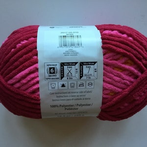 May include: A ball of pink and orange super bulky yarn with a label that says "Juicy Stripes" and "100% Polyester". The label also includes care instructions and knitting gauge information.