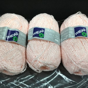 May include: Three balls of pink yarn labelled "Phildar Skate" with a green and blue logo. Each ball weighs 1 oz and contains 137 yards of yarn.