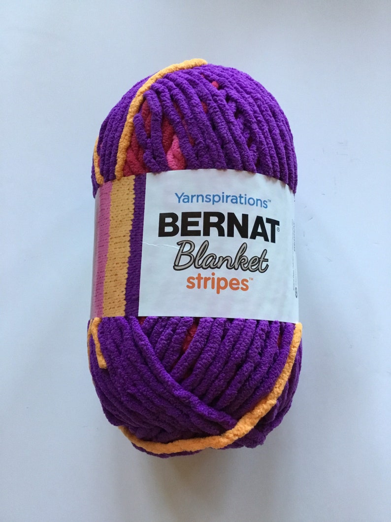 May include: A ball of purple, pink, and orange yarn with the label "Yarnspirations Bernat Blanket Stripes" on it.