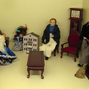 Puede incluir: Un conjunto de sala de estar de casa de mu&ntilde;ecas con una familia de mu&ntilde;ecas, muebles y un perro. Los muebles est&aacute;n hechos de madera y pintados de color marr&oacute;n oscuro. La familia de mu&ntilde;ecas est&aacute; vestida con ropa vintage. El perro es un carlino marr&oacute;n y blanco.