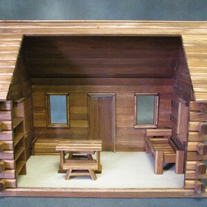 Finished 1-inch scale Crocketts Log Cabin Dollhouse Kit by Real Good Toys. Rear, inside view of log cabin dollhouse with one-room including log furniture. 13.5 inches tall x 18 wide. Kit sold unfinished.