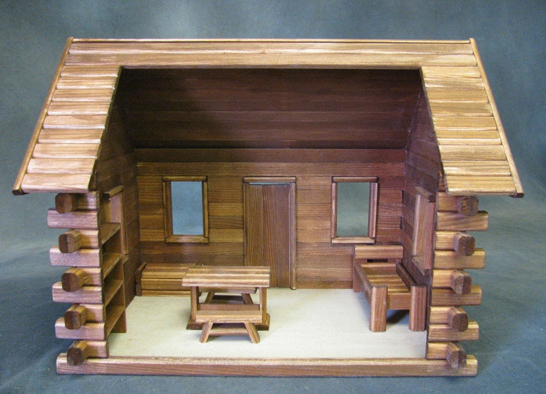 Finished 1-inch scale Crocketts Log Cabin Dollhouse Kit by Real Good Toys. Rear, inside view of log cabin dollhouse with one-room including log furniture. 13.5 inches tall x 18 wide. Kit sold unfinished.