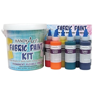 May include: A set of six fabric paint bottles in a variety of colors, including red, orange, yellow, teal, blue, and purple. The bottles are labeled "Handy Art Fabric Paint" and are arranged in a row on a white surface. The paint is designed for use on fabric and is heat-setting.