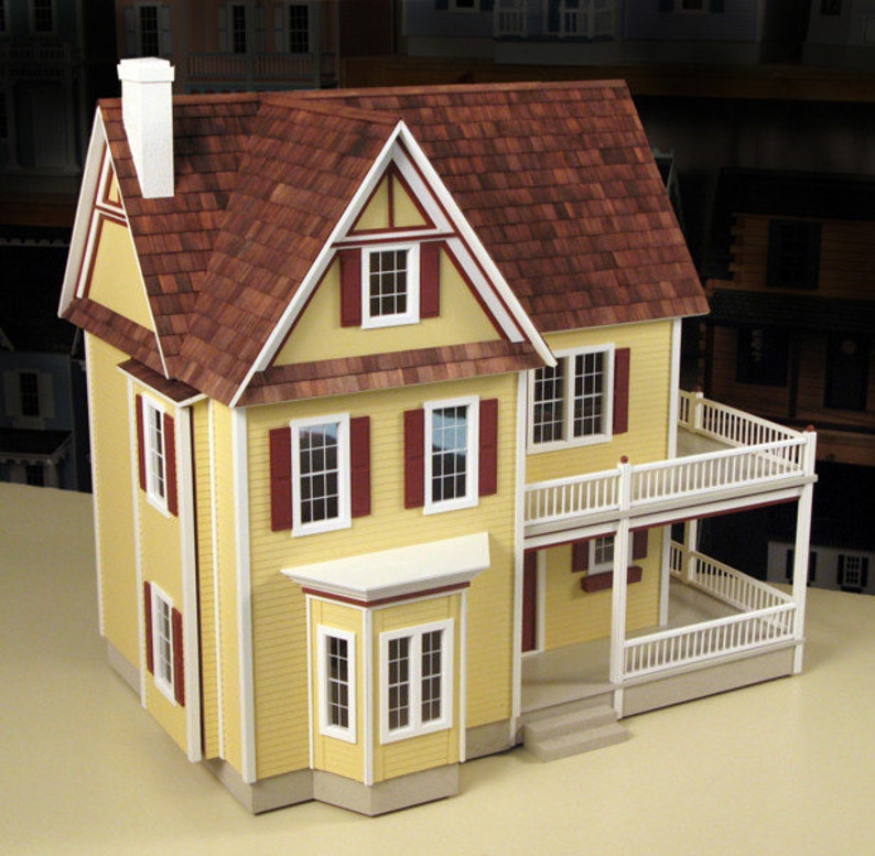 Front view of finished 1 inch scale Victorias Farmhouse Dollhouse Kit by Real Good Toys. 3 story farmhouse 33 in. tall x 34.5 wide. Milled clapboard exterior, wrap around porch, wooden roof shingles. Side opening access. Kit is unfinished.