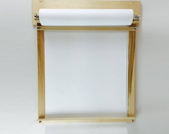 May include: A wooden wall-mounted paper roll holder with a white paper roll. The holder has a simple design with a wooden frame and a metal roller.