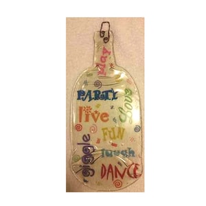 Könnte beinhalten: Ein durchsichtiges, flaschenförmiges Serviertablett aus Glas mit einem Drahtgriff. Die Flasche ist mit bunten Wörtern wie "Party", "Live", "Fun", "Giggle", "Dance" und "Savor" verziert.