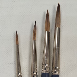 Może przedstawiać: Cztery pędzle z niebieskimi uchwytami i złotym napisem. Pędzle są oznaczone "SOC.INT.CAN.MTL. 68 SABEL" i mają nadrukowane na uchwytach numery 3, 5, 7 i 9.