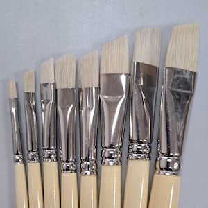 Może przedstawiać: Zestaw ośmiu pędzli z drewnianymi uchwytami i białymi włosiem. Uchwyty są oznaczone tekstem "SOC. INT. CAN. TOBGI MTL. 20121 Niemcy".