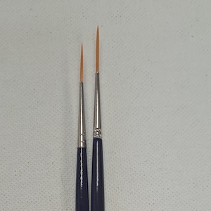 May include: Two paint brushes with black handles and gold lettering. The larger brush is labelled "0/20C M.I. C.A.U.". The smaller brush is labelled "1/10C CAN TOCCI HT"