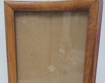 May include: A curved wooden picture frame with a light brown finish. The frame is empty and has a glass front.