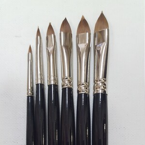 May include: A set of seven black handled paint brushes with gold lettering. The brushes are labeled with the numbers 2, 4, 6, 8, 10, and 12. The lettering on the brushes reads "SOC. INT. CAN. TODO MIL" and "SOC. INT. CAN. MTL. 1789".
