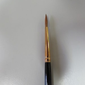 Może przedstawiać: Czarny i złoty pędzel z etykietą rozmiaru 3. Pędzel ma okrągły czubek i długi, cienki trzonek.