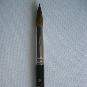 Może przedstawiać: Czarny i srebrny pędzel z brązowym włosiem. Pędzel jest oznaczony "12" i "SOC. INT. CAN. MTL. B."