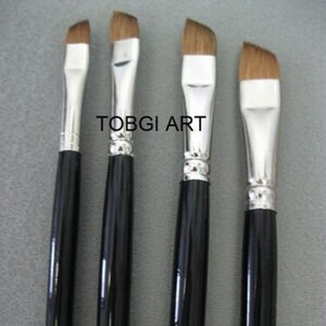 Op de afbeelding: Vier verfkwasten met zwarte handvatten en gouden letters. De kwasten zijn gemarkeerd met 1/2, 1, 10 en 12. De kwasten zijn in een rij van links naar rechts gerangschikt.