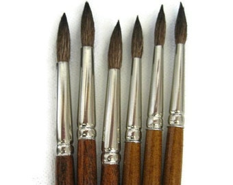 May include: A set of six artist paint brushes with natural bristles. The brushes have silver ferrules and dark brown wooden handles. The handles are labeled with the number 7 and the text "STE INT. CAN. TOBGI MTL".