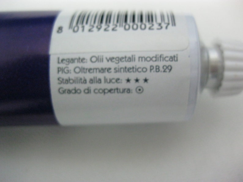 May include: A white tube of paint with a blue cap. The label reads "Legante: Olii vegetali modificati PIG: Oltremare sintetico P.B.29 Stabilit&agrave; alla luce: *** Grado di copertura: ".