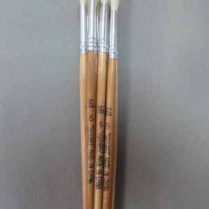 May include: Five wooden-handled paint brushes with white bristles. The brushes are bundled together and have the text "Squirrel Made in China" printed on the handles.