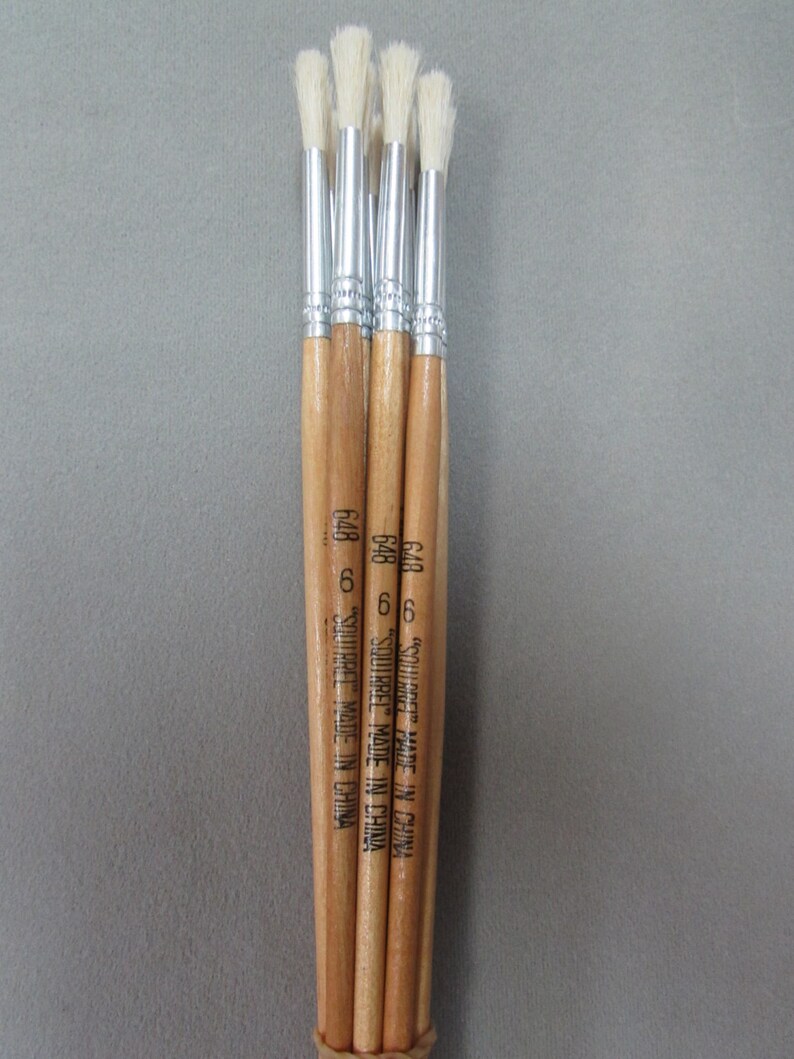 May include: Five wooden-handled paint brushes with white bristles. The brushes are bundled together and have the text "Squirrel Made in China" printed on the handles.