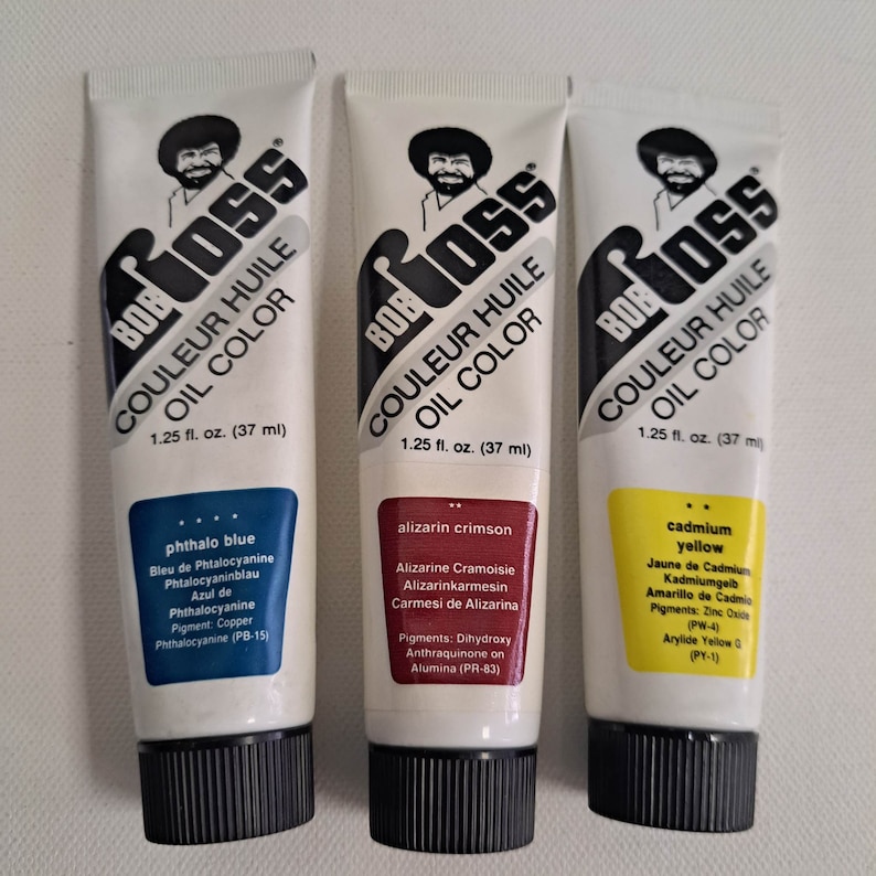 May include: Three tubes of Bob Ross brand oil paint. The tubes are labeled with the color names: Phthalo Blue, Alizarin Crimson, and Cadmium Yellow. Each tube contains 1.25 fluid ounces (37 ml) of paint.