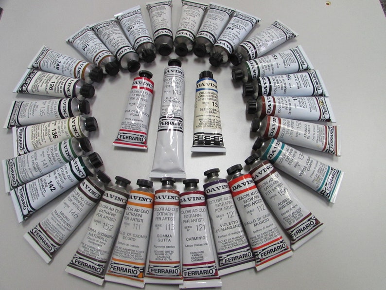 May include: A collection of 28 tubes of Da Vinci Extra Fine Artist Oil Colors arranged in a circle. The tubes are labeled with numbers and color names, such as 111, 112, 113, 115, 121, 126, 127, 135, 136, 140, 141, 142, 146, 149, 150, 152, 156, and 16. The tubes are all the same size and shape, and they are arranged in a circle with the caps facing outwards.