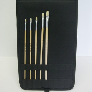 May include: A black canvas roll-up case with six paint brushes. The brushes are all different sizes and have wooden handles with the text "TOYO" printed on them.
