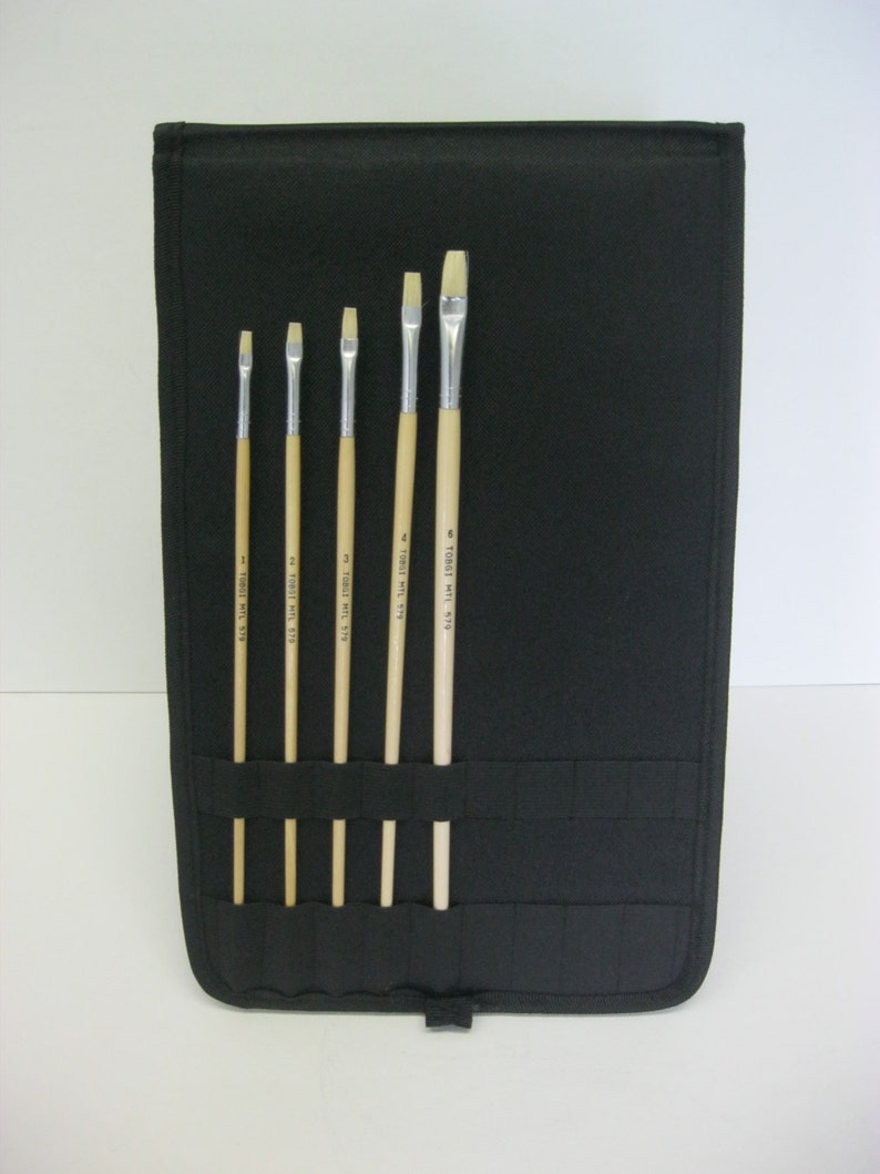 May include: A black canvas roll-up case with six paint brushes. The brushes are all different sizes and have wooden handles with the text "TOYO" printed on them.