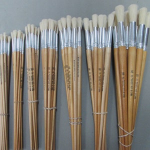 May include: A bundle of 20 round paint brushes with wooden handles and silver ferrules. The brushes are bundled together with rubber bands. The brushes are all the same size and have white bristles.