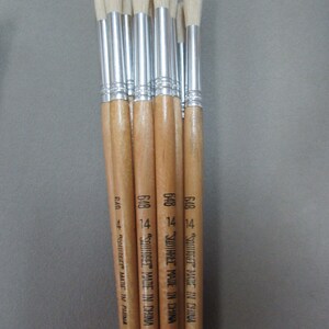May include: A set of eight paint brushes with wooden handles and white bristles. The handles are labeled "SQUIRREL MADE IN CHINA" and "648 14".