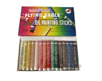 Op de afbeelding: Een doos met 15 niet-giftige olieverf-stokken in verschillende kleuren. De doos is gelabeld met "Flying Eagle" en "Artistic Oil Painting Sticks".
