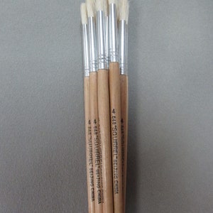 May include: A bundle of six paint brushes with wooden handles and silver ferrules. The brushes have white bristles and are labeled "648 "SQUIRREL" BEIJING CHINA".