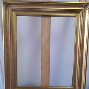 May include: A gold picture frame with a simple, ornate design. The frame is made of wood and has a smooth, polished finish.
