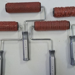 May include: Five different textured paint rollers with handles. The rollers are red and have different patterns. The handles are silver and have labels with the text "Model # 3", "Model # 4", "14" "24" and "24".
