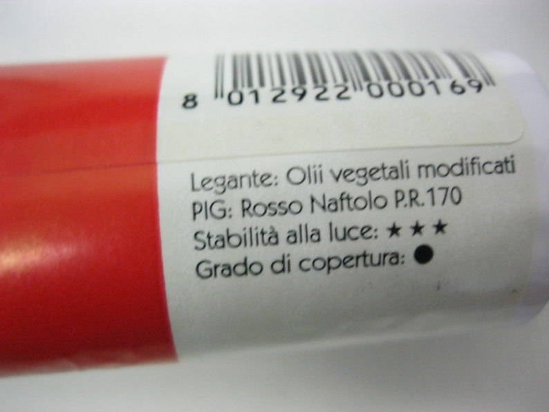 May include: A red paint tube with a white label. The label includes the text "Legante: Olii vegetali modificati", "PIG: Rosso Naftolo P.R.170", "Stabilit&agrave; alla luce: ★★★", and "Grado di copertura:".