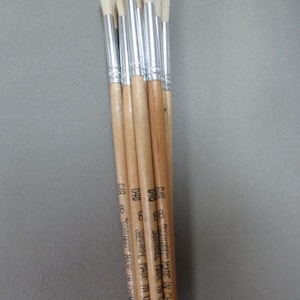 May include: A bundle of seven paint brushes with wooden handles and white bristles. The handles are labeled "Squirrel" and "Made in China".