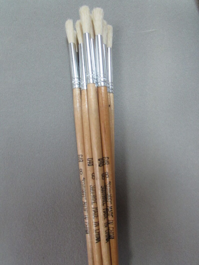 May include: A bundle of seven paint brushes with wooden handles and white bristles. The handles are labeled "Squirrel" and "Made in China".