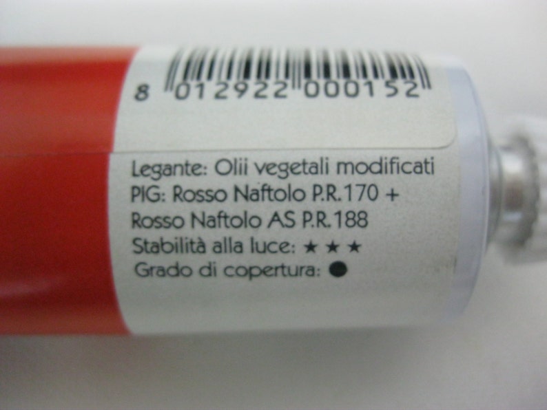 May include: A white tube of red paint with a label that reads "Legante: Olii vegetali modificati PIG: Rosso Naftolo P.R.170 + Rosso Naftolo AS P.R.188 Stabilit&agrave; alla luce: ★★★ Grado di copertura: ".