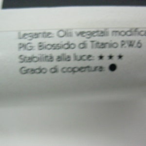 May include: A close-up of a white tube with black text. The text reads: "Legante: Oli vegetali modificati PIG: Biossido di Titanio P.W.6 Stabilit&agrave; alla luce: *** Grado di copertura: 50 ML"
